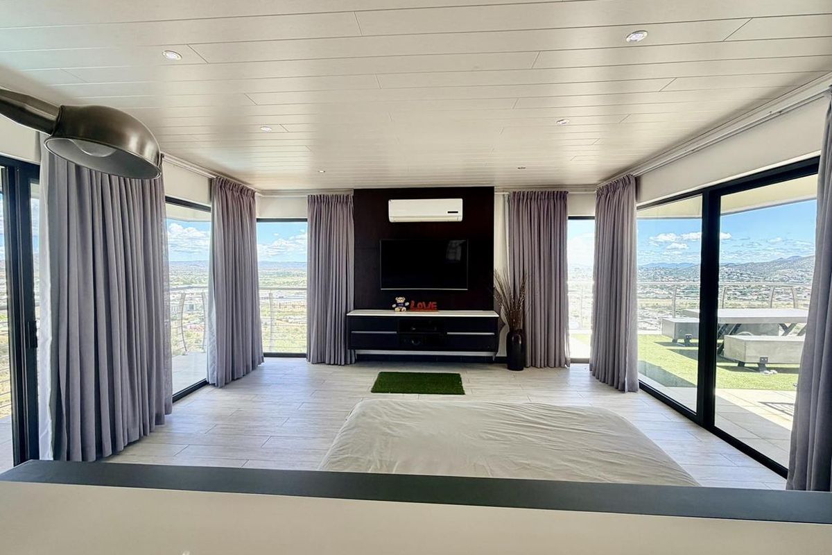 Spacious living area featuring floor-to-ceiling glass sliding doors, panoramic views, recessed ceiling lighting, and a modern wall-mounted air conditioning unit.
