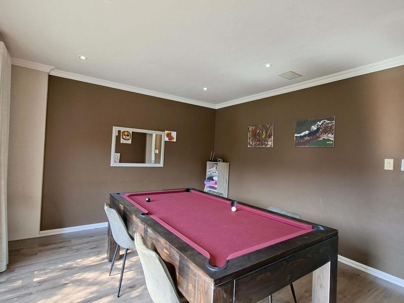 Spacious living area featuring laminate flooring, recessed downlighting, crown molding, and a large sliding glass door providing natural light.