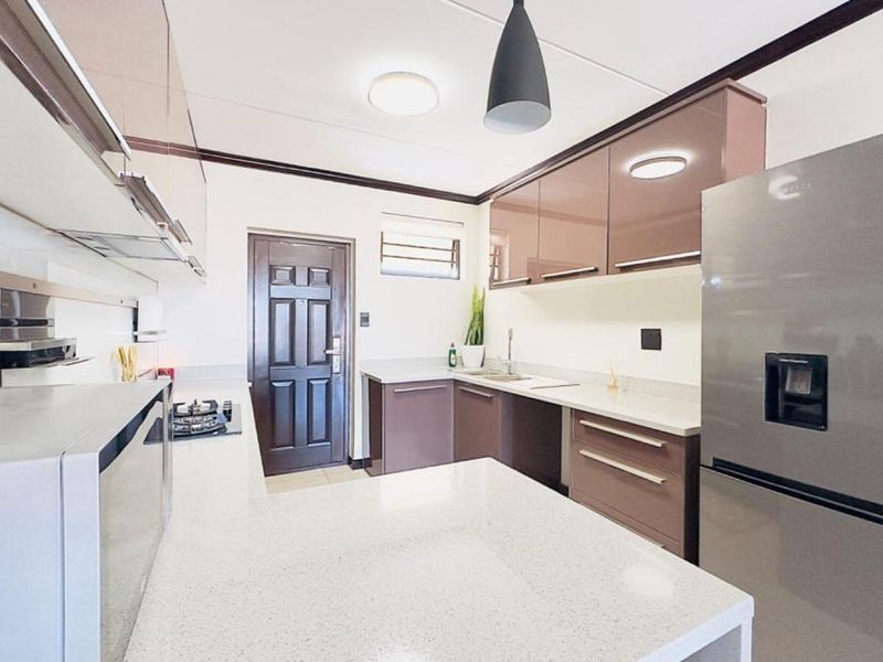 Modern kitchen featuring sleek glossy cabinetry, quartz countertops, a gas hob, and integrated extractor fan, offering a clean and functional culinary space.