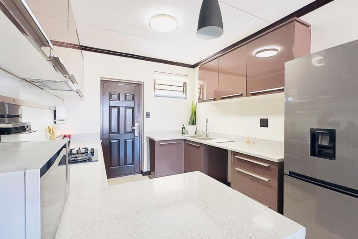 Modern kitchen featuring sleek glossy cabinetry, quartz countertops, a gas hob, and integrated extractor fan, offering a clean and functional culinary space.