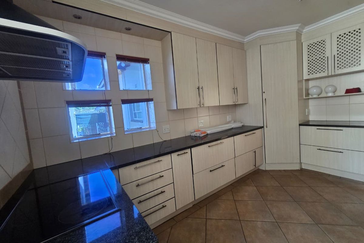 A functional kitchen featuring light-toned cabinetry, dark granite countertops, tiled backsplash, and ceramic floor tiles, offering a clean and well-maintained workspace.