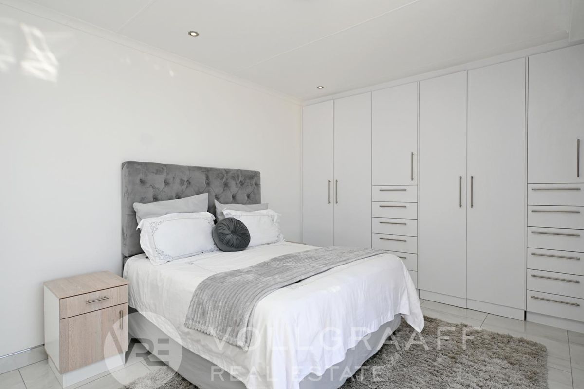 A bright bedroom featuring extensive built-in floor-to-ceiling cabinetry with integrated drawers and recessed downlighting.