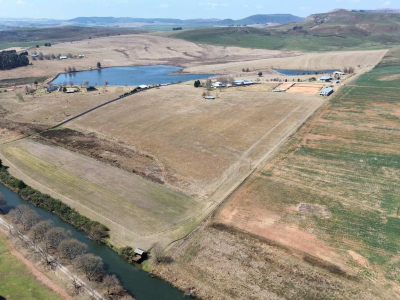 Aerial view of a large farm property featuring expansive grazing land, river frontage, multiple dams, and established equestrian facilities.