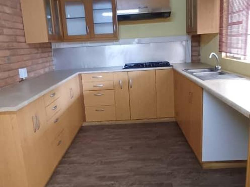 Kitchen featuring exposed brickwork, timber beams, laminate cabinetry, gas hob, and stainless steel sink, offering a rustic aesthetic with potential for modern updates.