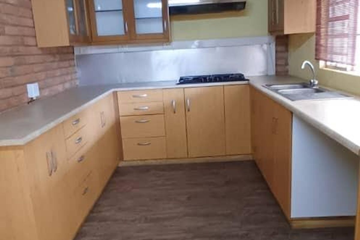 Kitchen featuring exposed brickwork, timber beams, laminate cabinetry, gas hob, and stainless steel sink, offering a rustic aesthetic with potential for modern updates.
