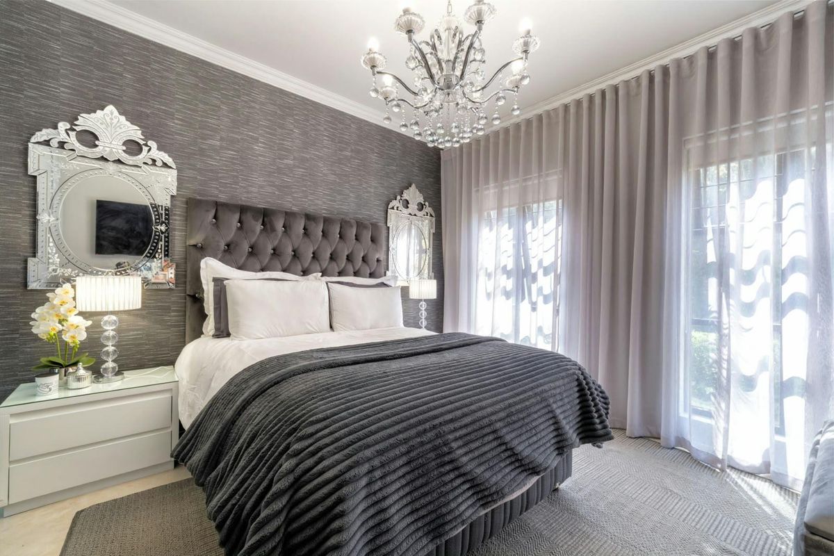 A well-appointed bedroom featuring textured wallpaper, crown molding, and large sliding glass doors that provide ample natural light.