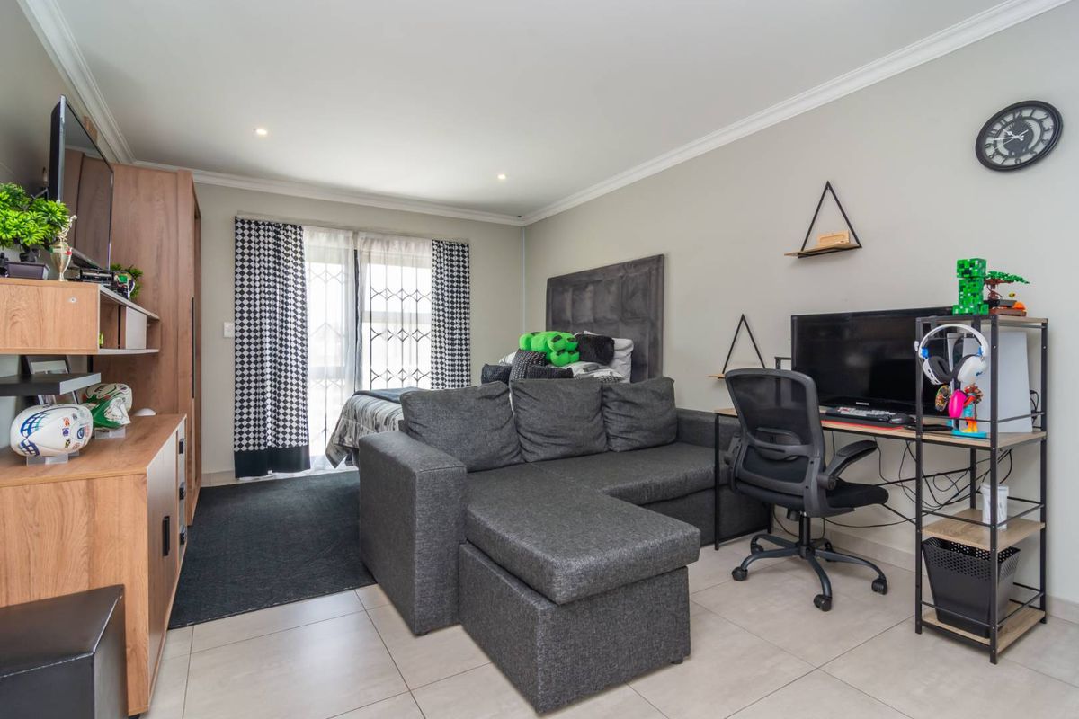 A well-maintained bedroom featuring tiled flooring, recessed lighting, and a sliding glass door with security gate providing access to the exterior.
