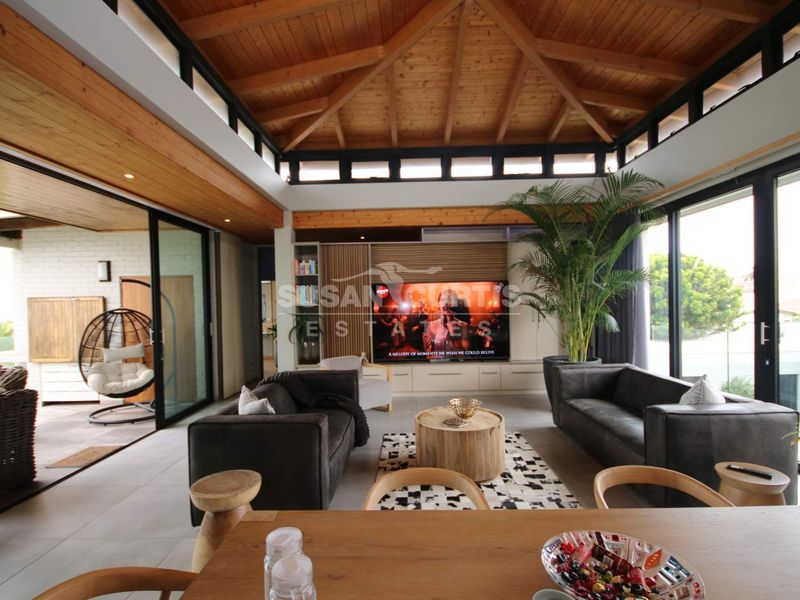 Spacious open-plan living area featuring a striking exposed timber vaulted ceiling, clerestory windows, and seamless indoor-outdoor flow through large sliding glass doors.