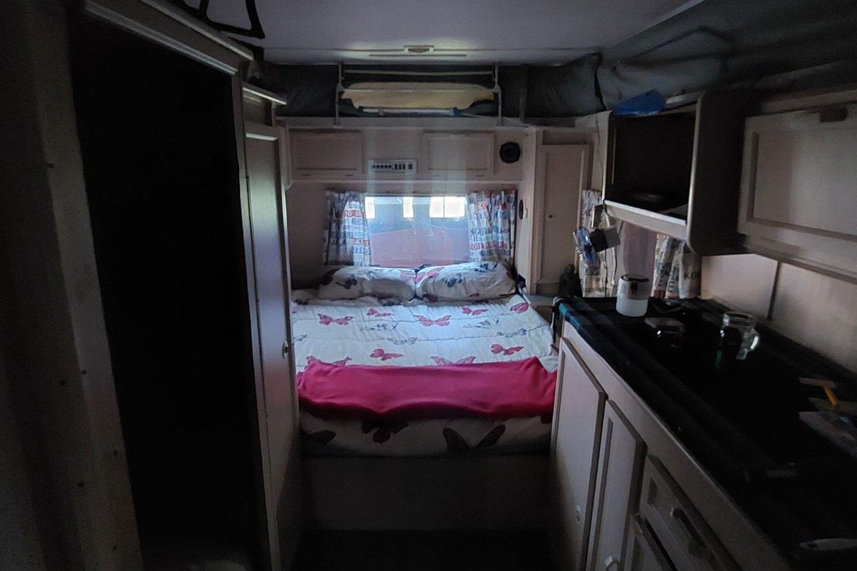 Interior view of a compact caravan bedroom area featuring built-in cabinetry and storage compartments.