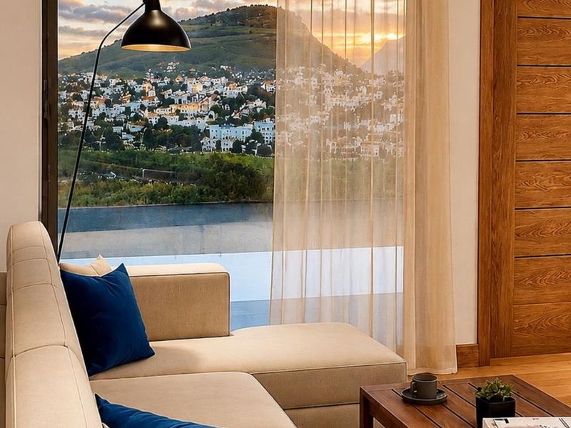 A modern living room featuring large floor-to-ceiling windows that frame a scenic mountain and town view, complemented by elegant wooden door finishes.