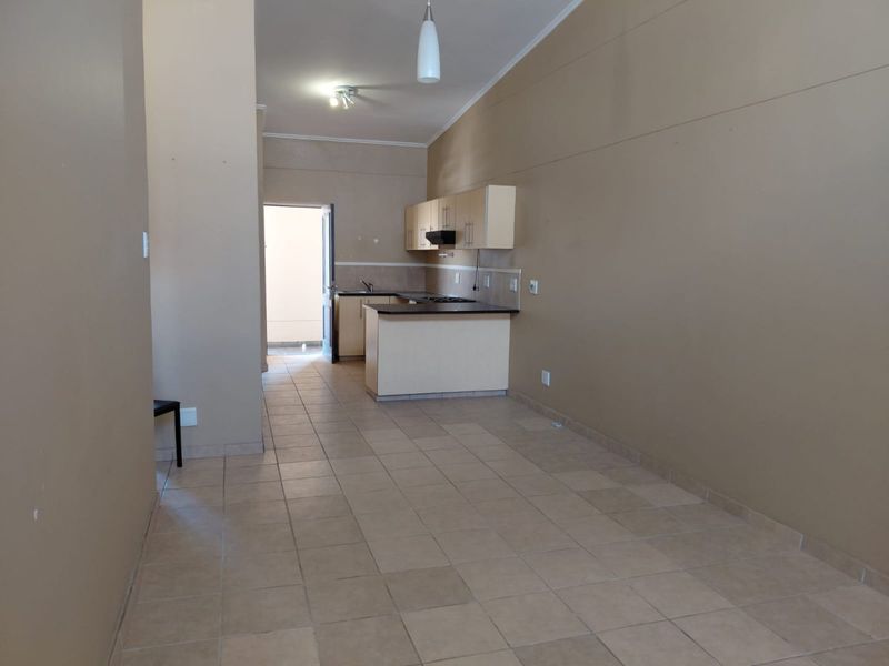 An open-plan living and kitchen area featuring tiled flooring, built-in cabinetry, and a functional kitchen peninsula, offering a blank canvas for personalization.