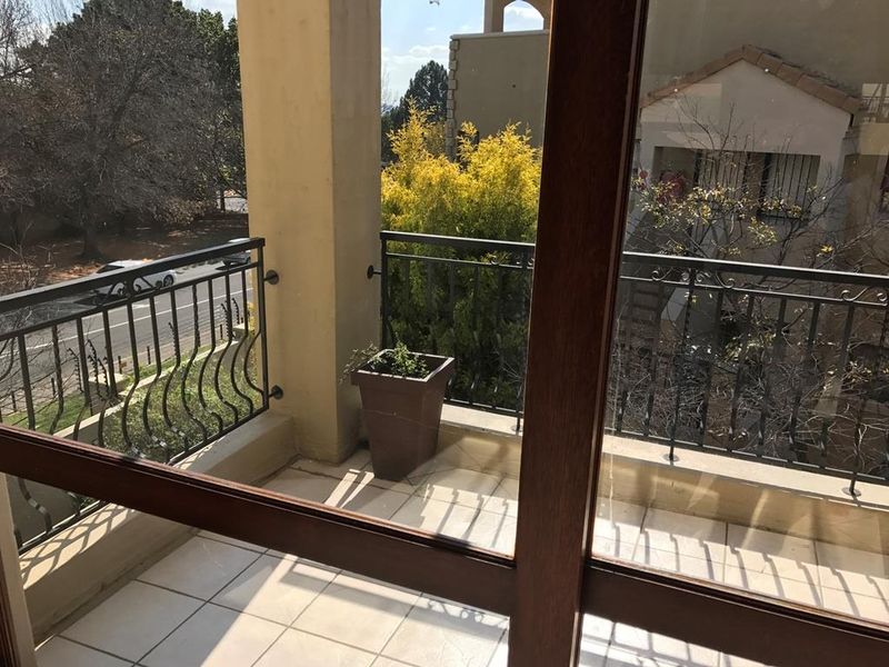 A private balcony featuring tiled flooring and a decorative wrought iron balustrade, accessible via a large sliding glass door.