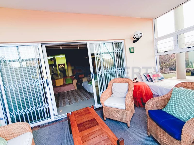A covered patio area featuring sliding glass doors with security gates, providing a seamless transition to the interior living space.