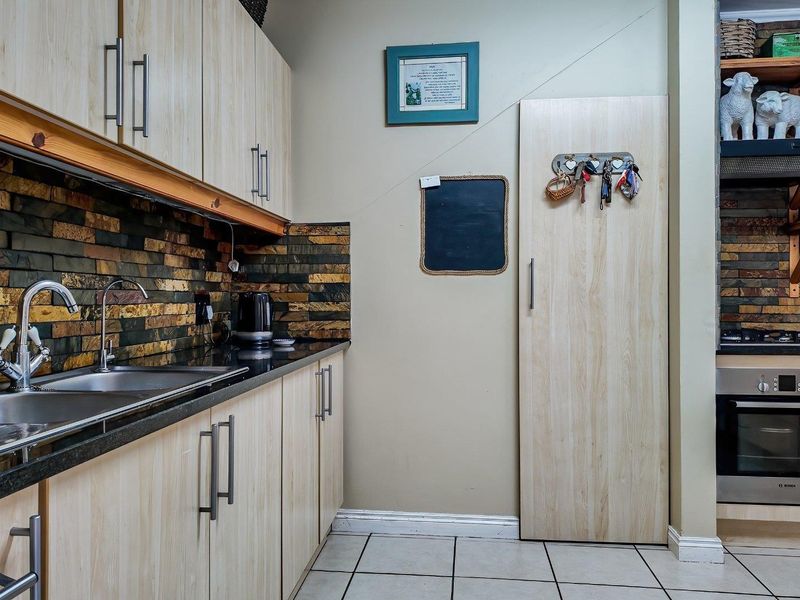 A functional kitchen featuring light wood-look cabinetry, granite countertops, a stone tile backsplash, and integrated stainless steel appliances.