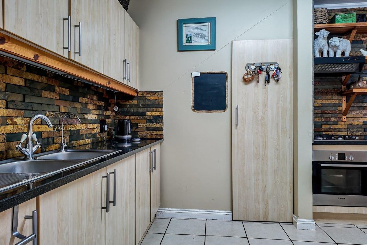 A functional kitchen featuring light wood-look cabinetry, granite countertops, a stone tile backsplash, and integrated stainless steel appliances.