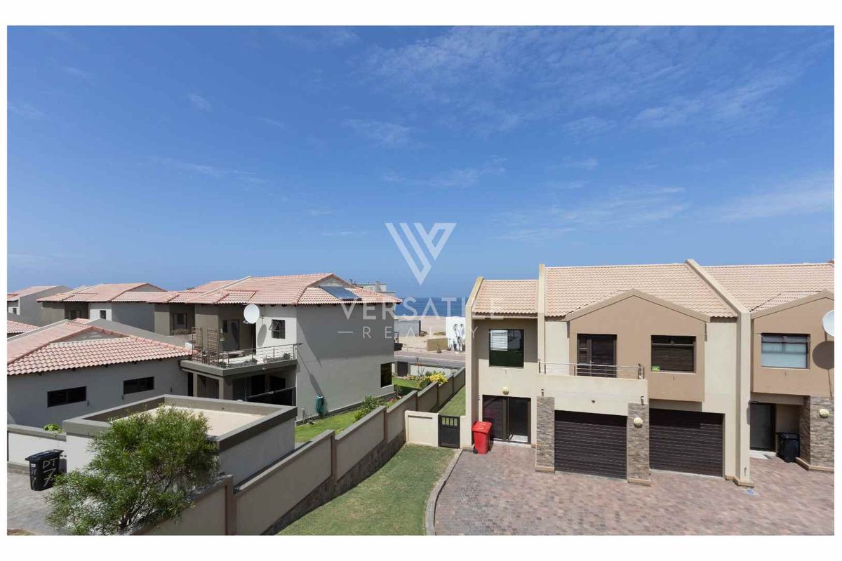 An elevated view of a modern townhouse complex featuring paved driveways, double garages, and tiled roof architecture.