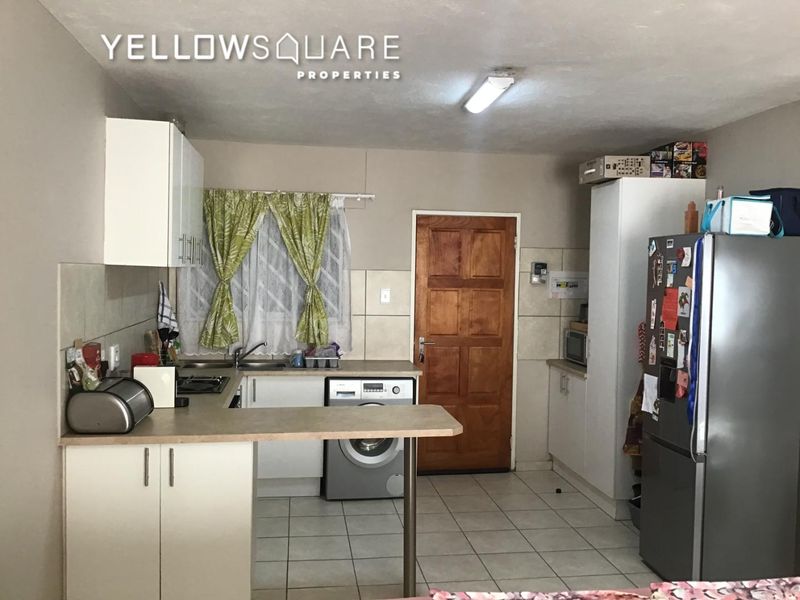 Functional kitchen featuring built-in cabinetry, laminate countertops, tiled backsplash, and integrated laundry plumbing, offering a practical layout for daily use.