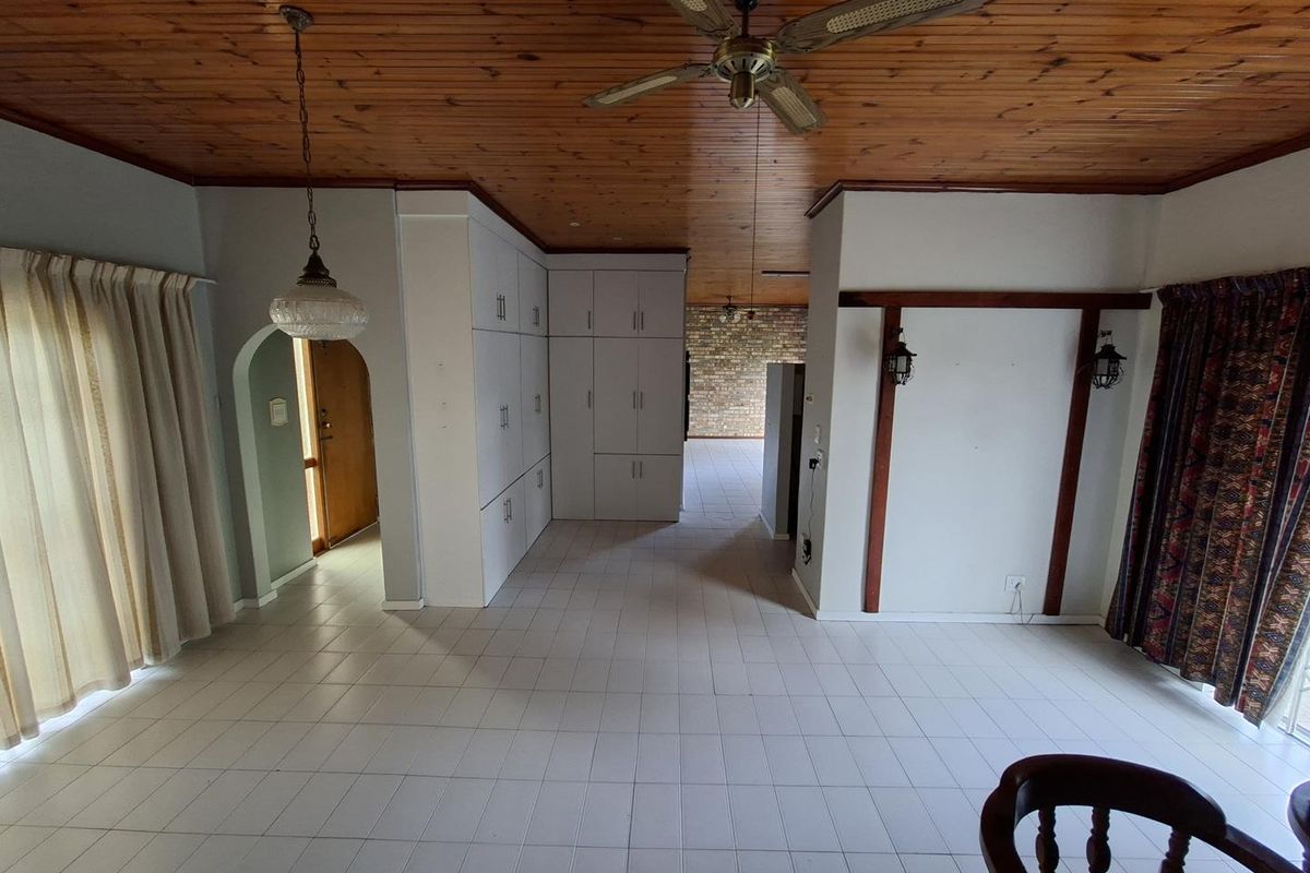 Spacious living area featuring a timber ceiling, ceiling fan, tiled flooring, and extensive built-in cabinetry, offering a versatile layout for interior design.