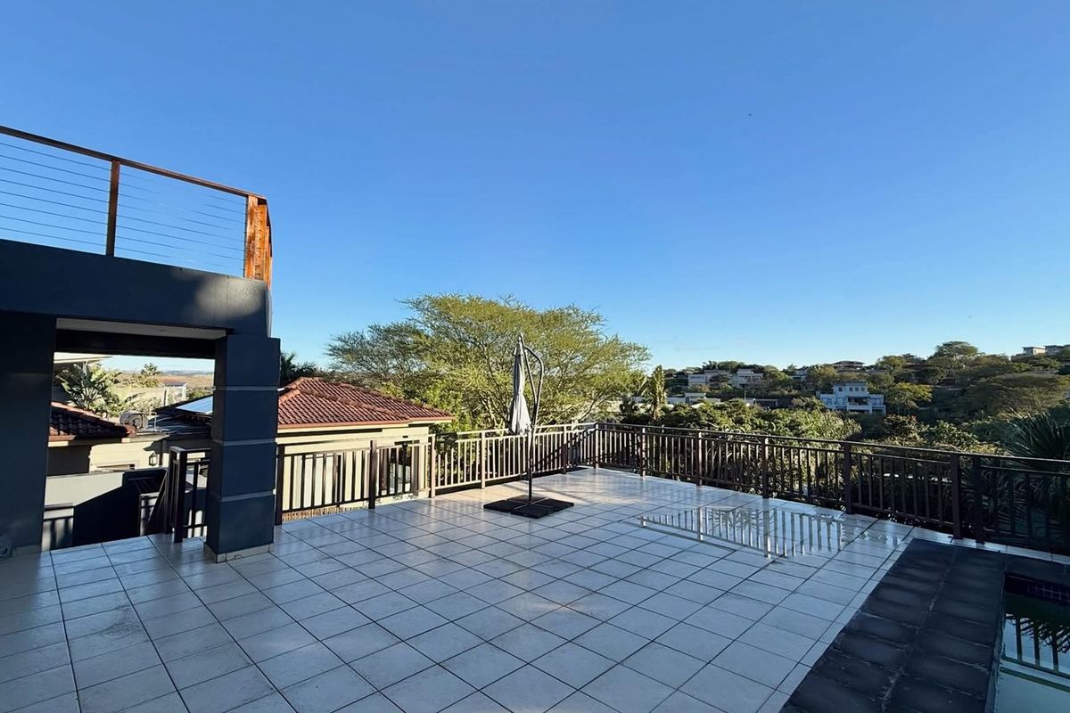 Spacious elevated patio featuring tiled flooring, metal balustrades, and an adjoining swimming pool with scenic neighborhood views.