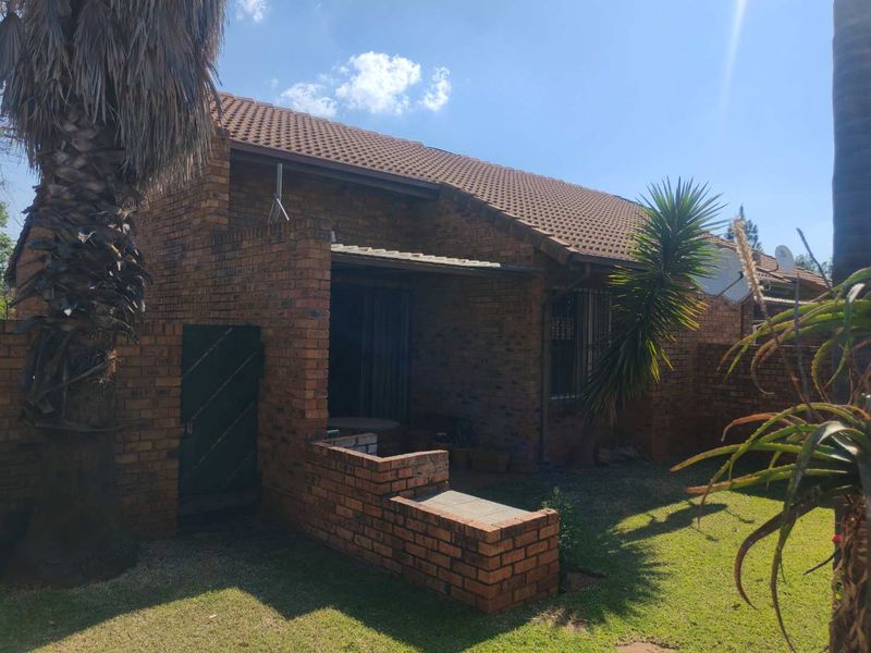 Rear view of a face brick townhouse featuring a covered patio area and a private garden space.