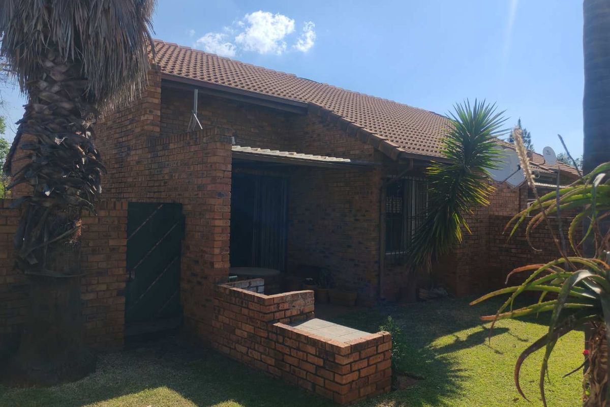 Rear view of a face brick townhouse featuring a covered patio area and a private garden space.