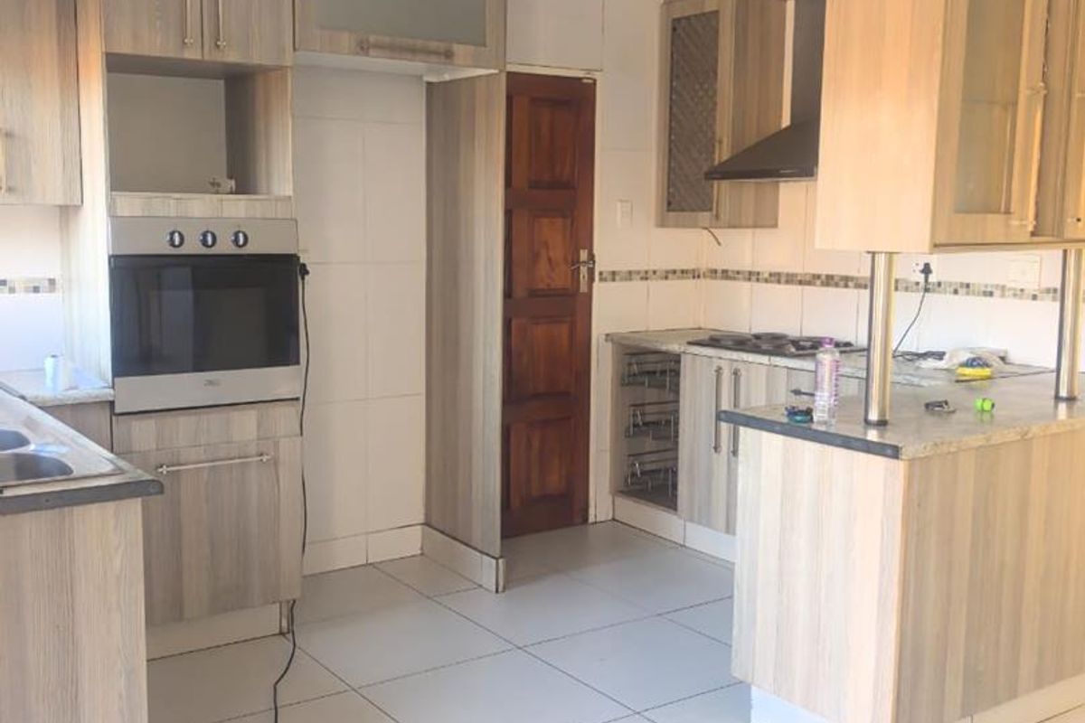 A functional kitchen featuring wood-look cabinetry, built-in oven, hob, and tiled flooring. The space requires minor repairs to the ceiling and electrical finishing.