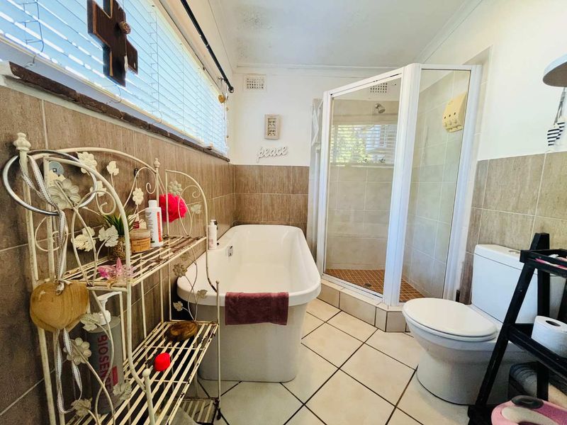 A functional bathroom featuring a freestanding bathtub, separate corner shower enclosure, tiled walls, and floor tiling.