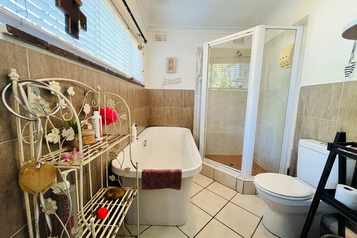 A functional bathroom featuring a freestanding bathtub, separate corner shower enclosure, tiled walls, and floor tiling.