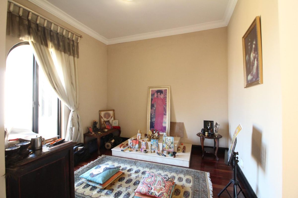 A quiet room featuring polished timber flooring, crown molding, and an arched window, currently utilized as a dedicated prayer or meditation space.