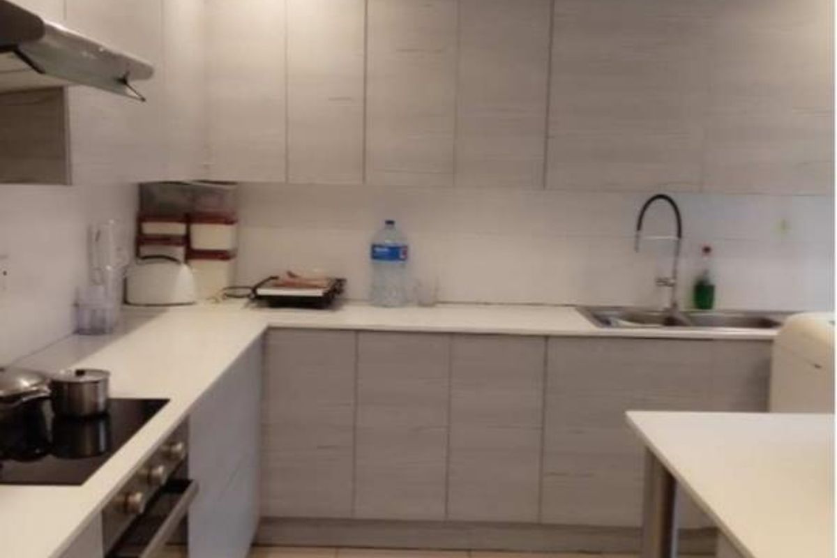 Modern kitchen featuring light wood-grain cabinetry, white countertops, integrated appliances, and tiled flooring with recessed lighting.