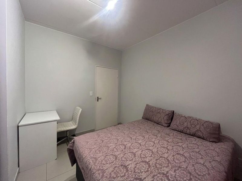 A simple bedroom featuring tiled flooring and neutral wall finishes, providing a functional space for rest.