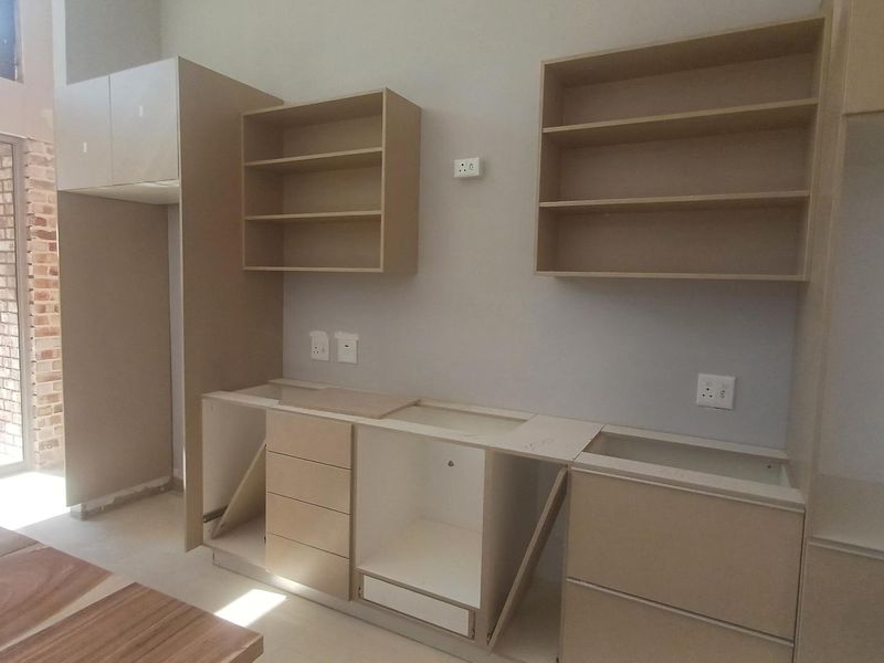 An unfinished kitchen area featuring installed base and wall cabinetry, awaiting countertops and final fittings to complete the space.