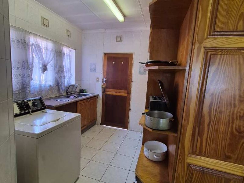 A functional laundry room featuring tiled flooring, built-in wooden shelving, and a sink, providing a practical space for utility and washing needs.