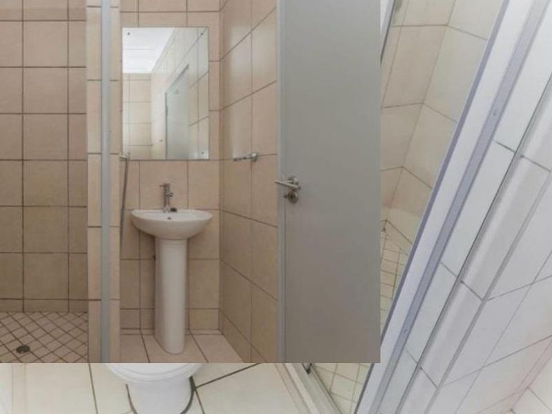A functional bathroom featuring a pedestal basin, shower enclosure, and tiled finishes throughout.