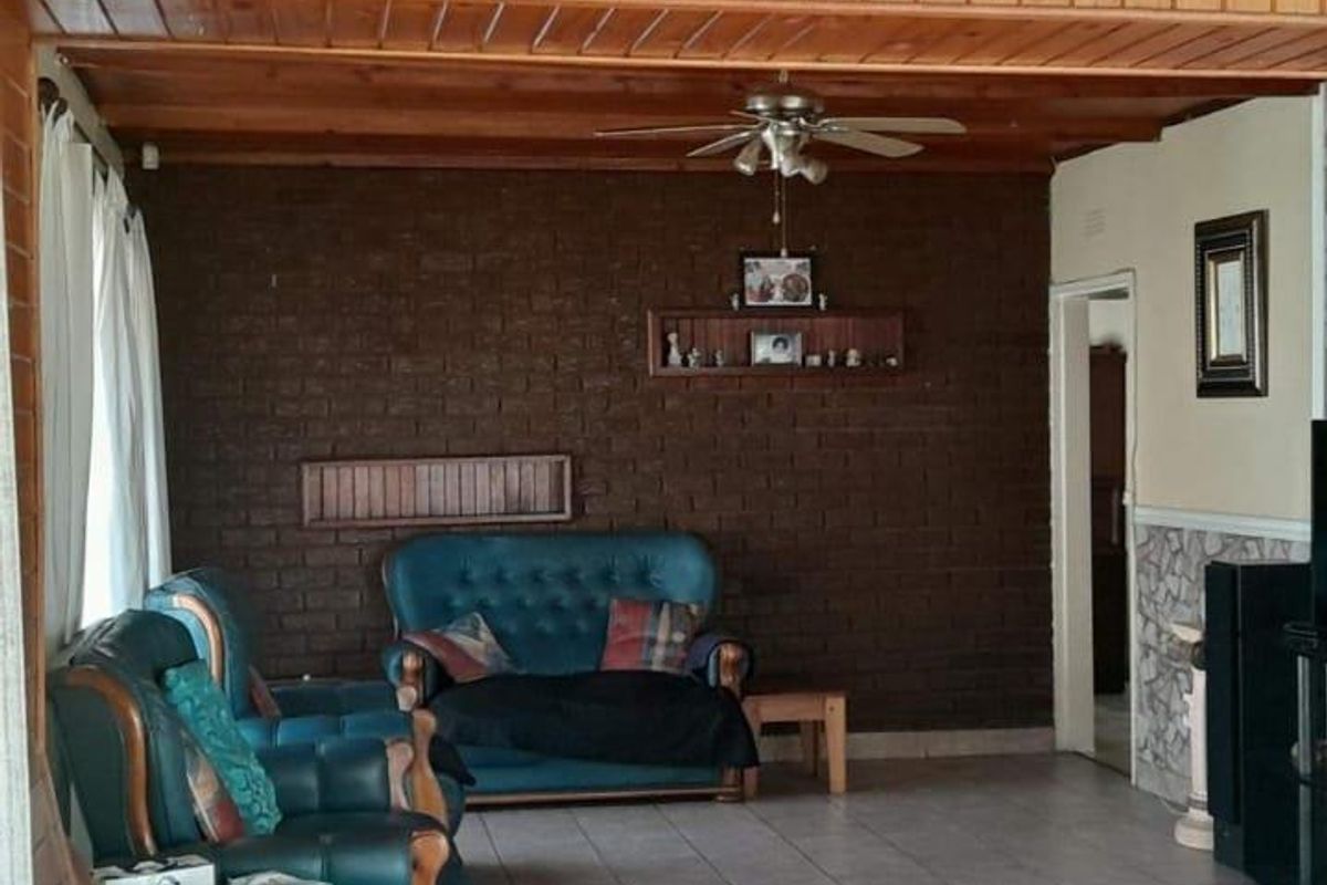 A living room featuring a dark brick feature wall, timber-clad ceiling with a mounted fan, and tiled flooring.