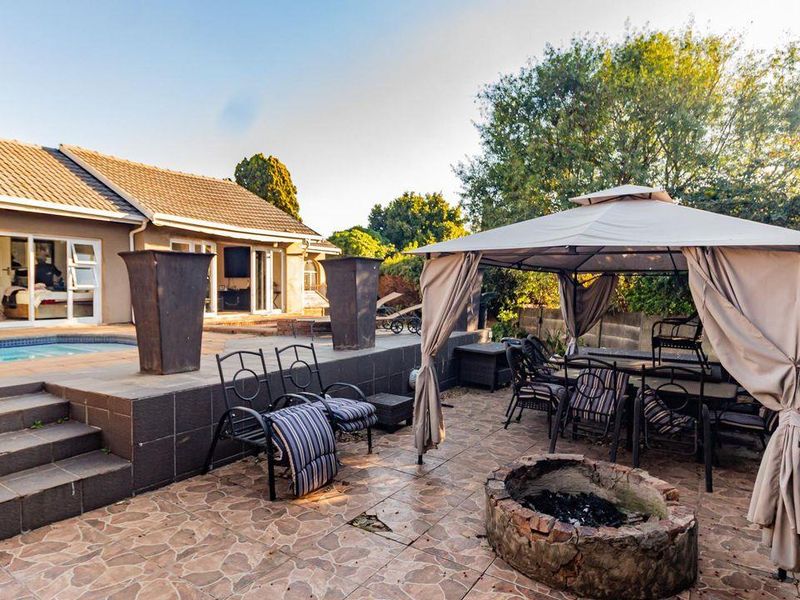 Rear outdoor entertainment area featuring a swimming pool, tiled patio, and a stone fire pit, providing a functional space for relaxation and social gatherings.