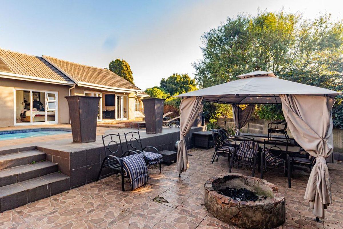 Rear outdoor entertainment area featuring a swimming pool, tiled patio, and a stone fire pit, providing a functional space for relaxation and social gatherings.