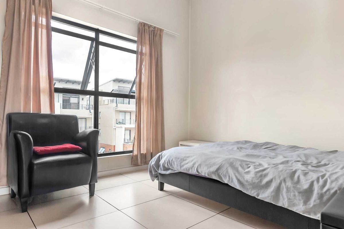 A bedroom featuring large windows with natural light, tiled flooring, and neutral wall finishes.
