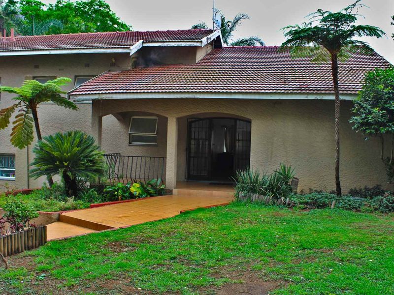 Front elevation of a residential house featuring a tiled roof, stucco exterior, and a covered entrance with a tiled walkway.