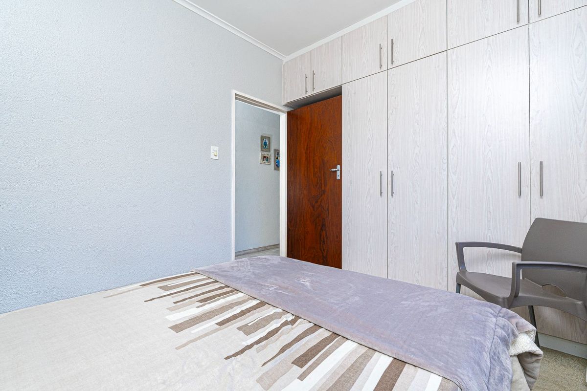 A bedroom featuring light-toned built-in cupboards and a wooden door, providing functional storage space.