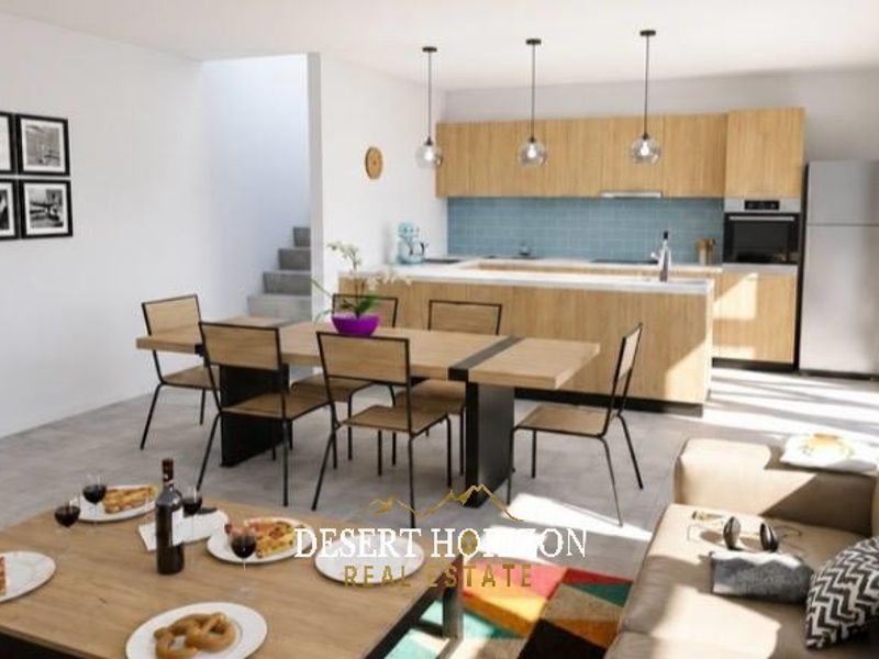 Modern open-plan living area featuring a contemporary kitchen with light wood cabinetry, a central island, and a seamless flow to the dining and lounge space.