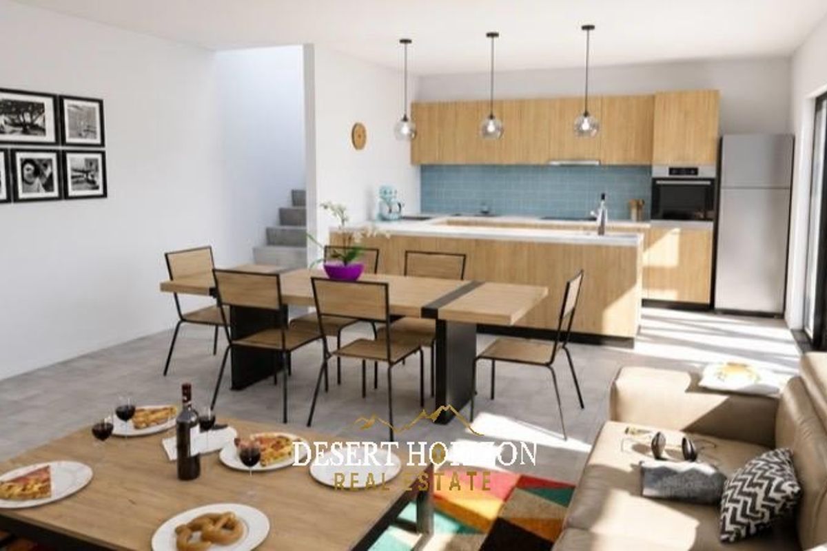 Modern open-plan living area featuring a contemporary kitchen with light wood cabinetry, a central island, and a seamless flow to the dining and lounge space.