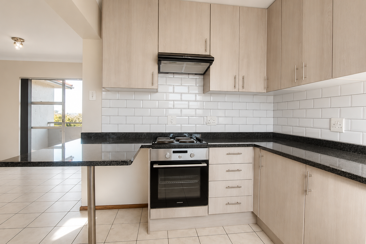 Modern kitchen featuring light wood cabinetry, granite countertops, subway tile backsplash, and integrated appliances, with an open-plan layout leading to the living area.