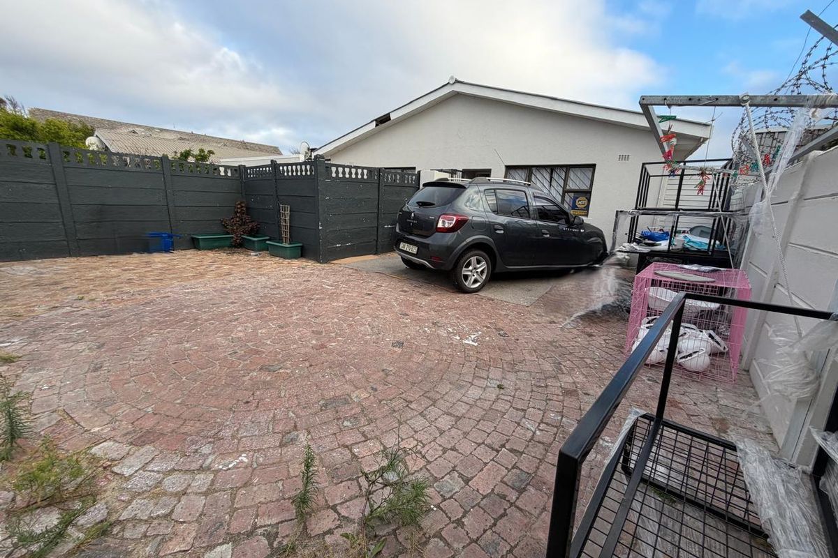 A paved rear courtyard area featuring perimeter fencing and direct access to the main dwelling structure.