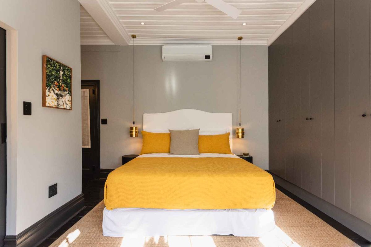 A well-appointed bedroom featuring extensive built-in cabinetry, modern split-system air conditioning, and elegant pendant lighting with a clean, contemporary finish.