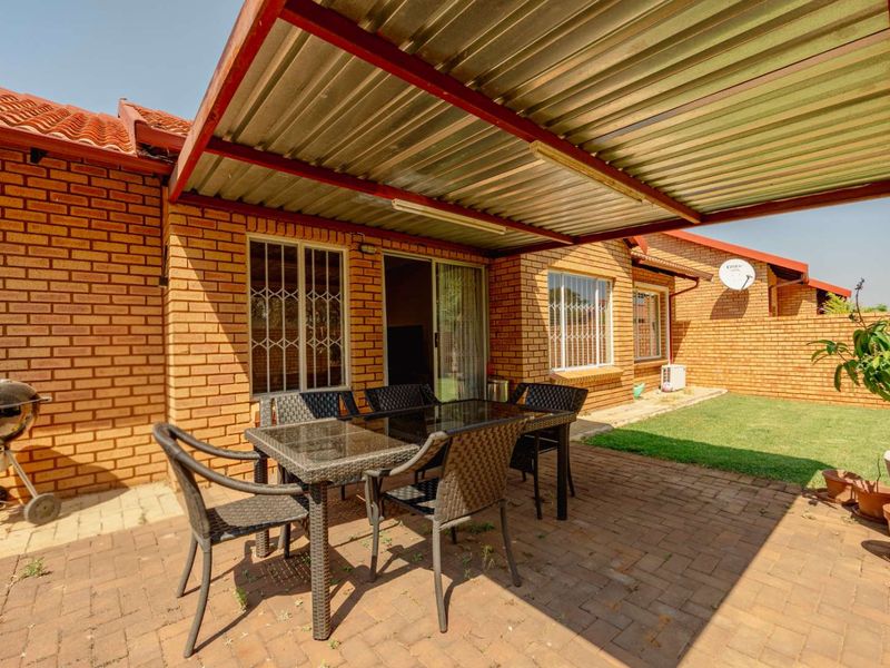 A covered patio area featuring brick paving and a corrugated metal roof, providing a functional outdoor space adjacent to the main dwelling.
