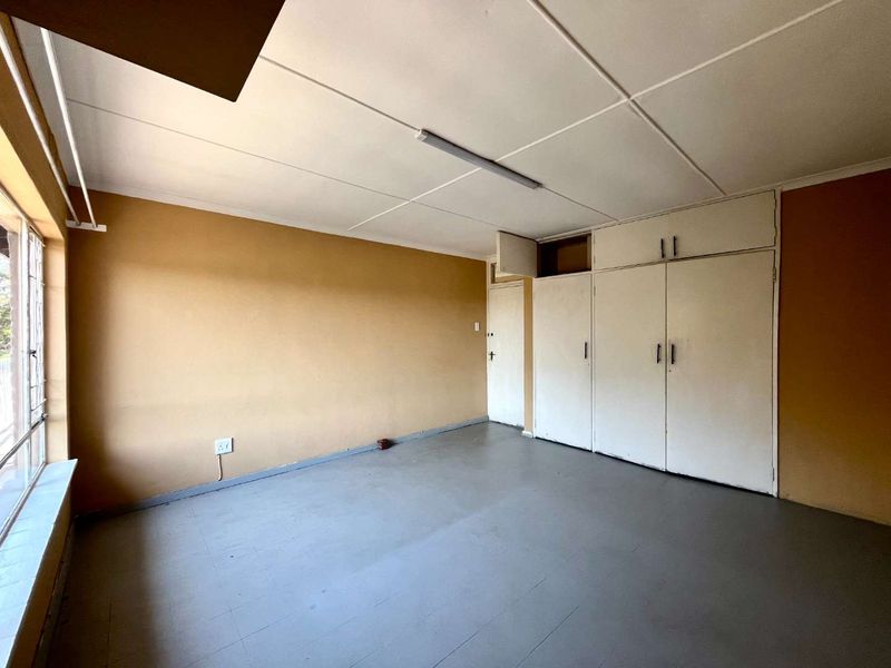 An empty bedroom featuring built-in cupboards, tiled flooring, and a neutral color palette, offering a blank canvas for renovation or interior design updates.