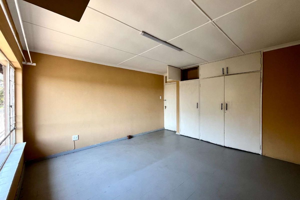 An empty bedroom featuring built-in cupboards, tiled flooring, and a neutral color palette, offering a blank canvas for renovation or interior design updates.