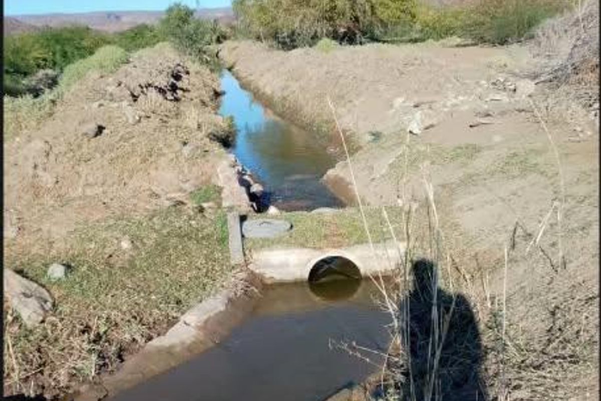 An irrigation water channel running through the small holding, featuring concrete culvert infrastructure and natural landscape surroundings.