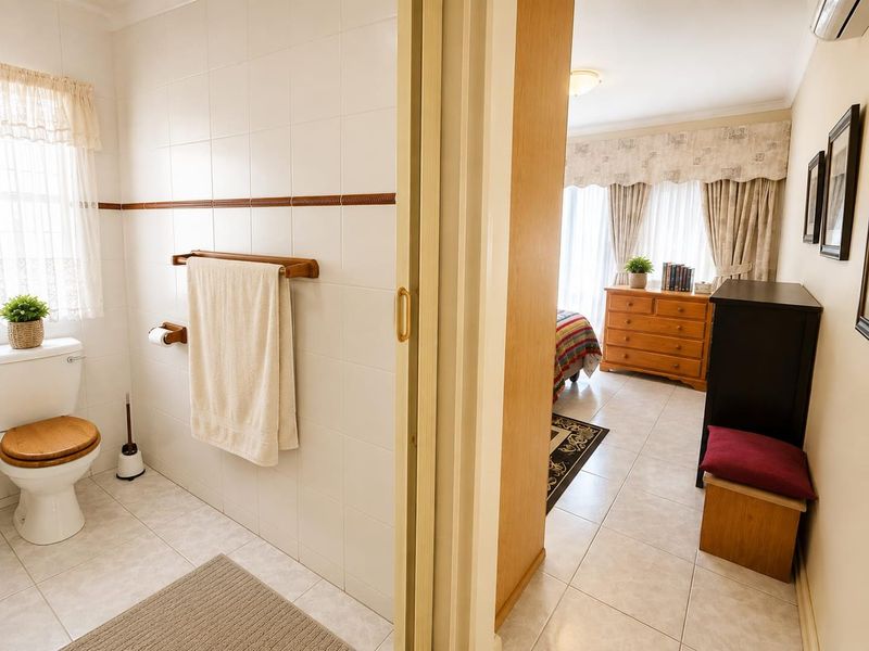 A functional bathroom featuring ceramic wall and floor tiles, adjacent to a bedroom area with a sliding door entry.
